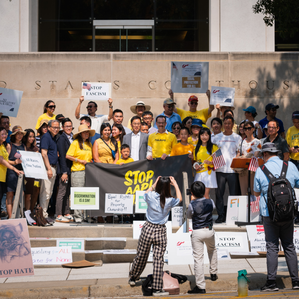 Image of a group of protestors holding signs and an American flag.